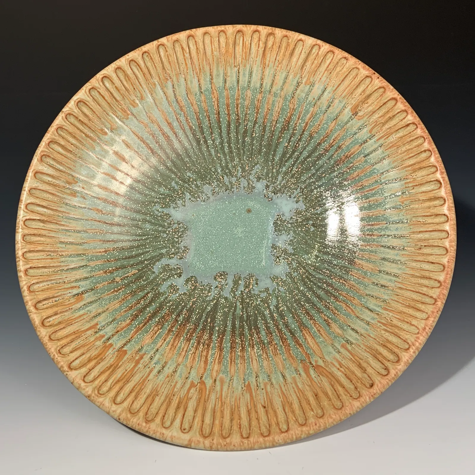 Willow bowl seen from above, with carved ochre lines radiating out from a jade green center.